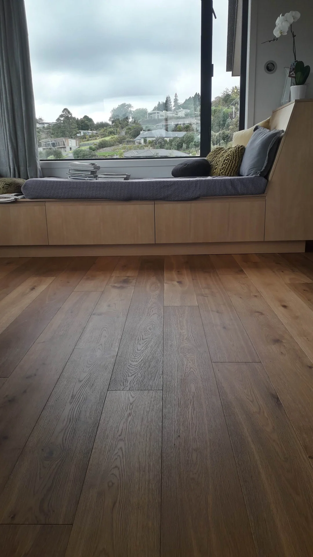 Dark oak floor under a window seat.
