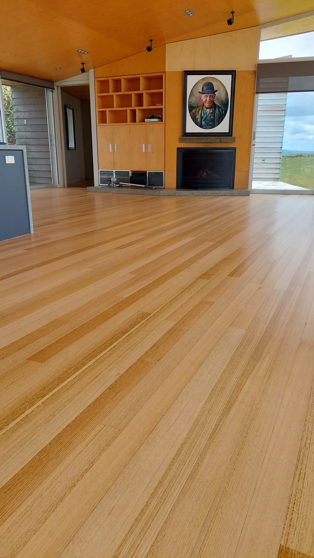 Blond timber floor to a fireplace wall.