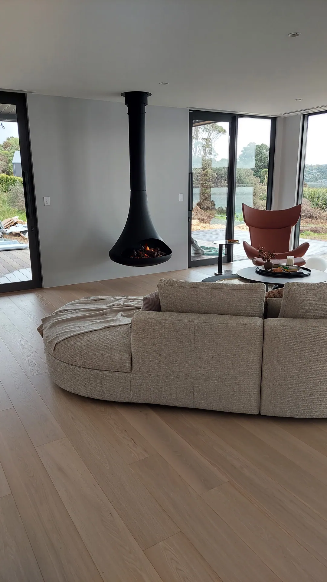 Light oak floor in a living room with a hanging fireplace.