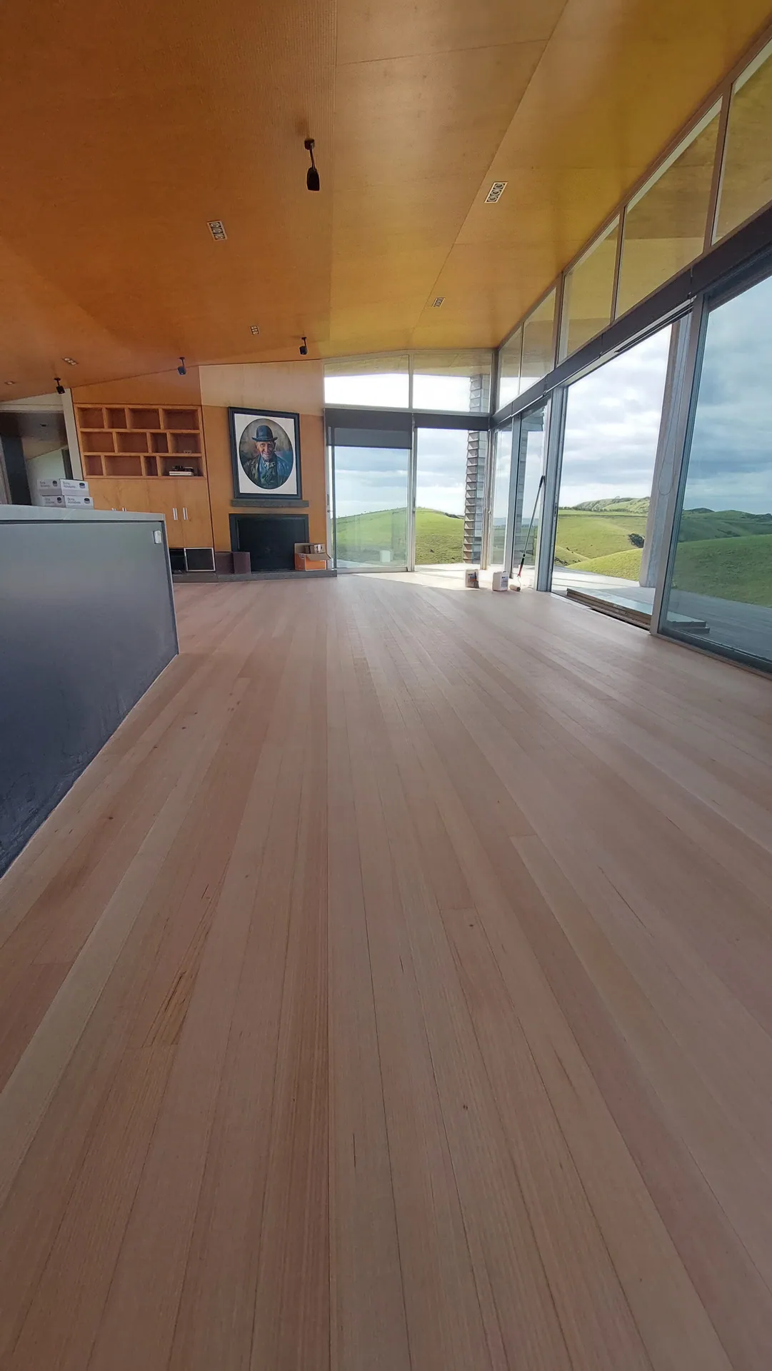 Long blond timber floor under a plywood ceiling.