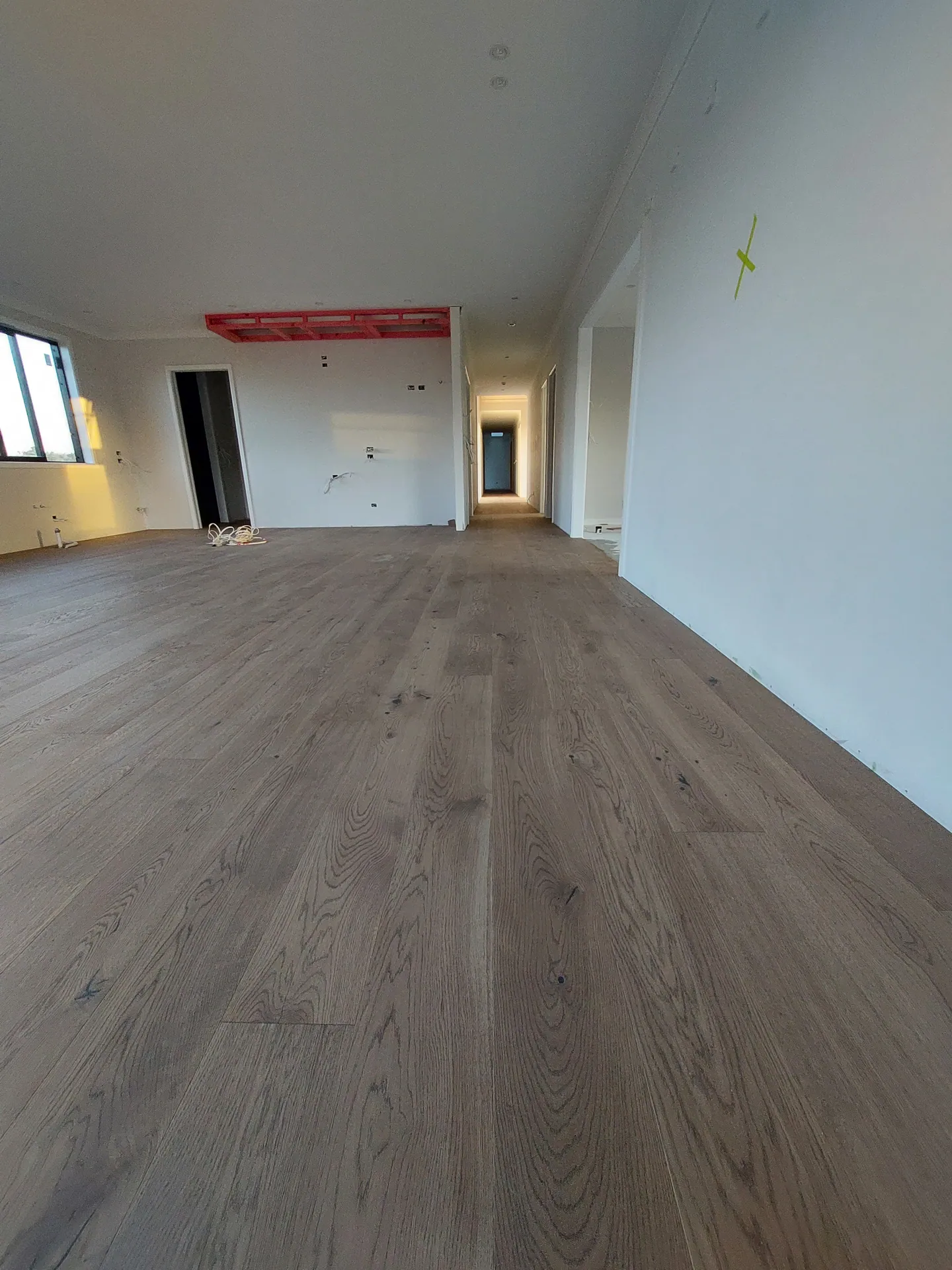 Wide open-plan room with a light oak floor in a new build awaiting its kitchen.