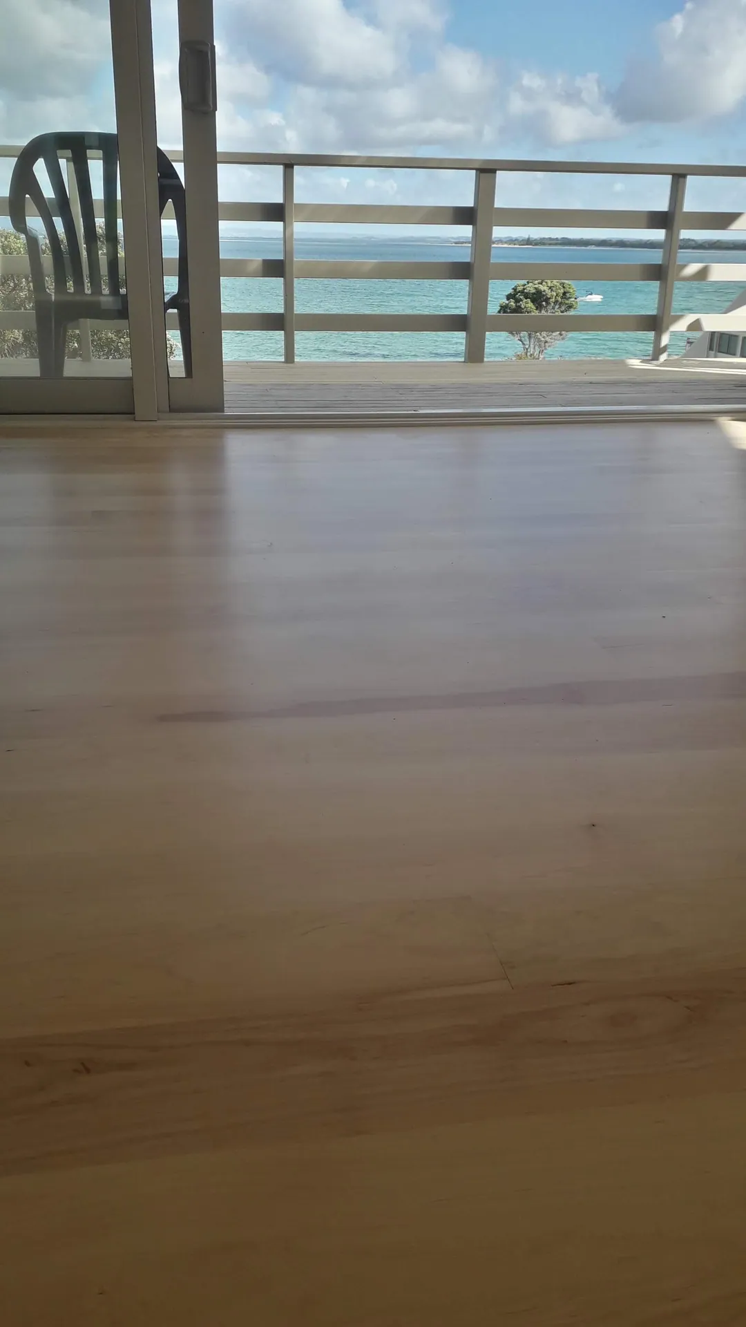 Satin timber floor out to a deck and the sea.