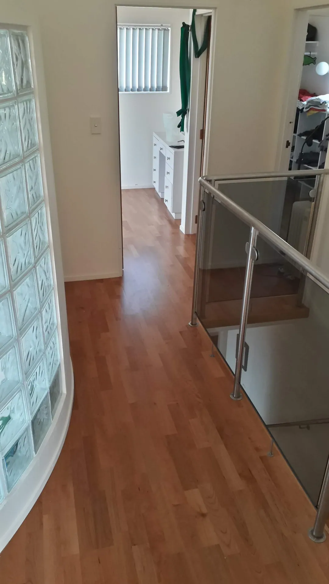 Timber hallway floor beside a glass block wall.