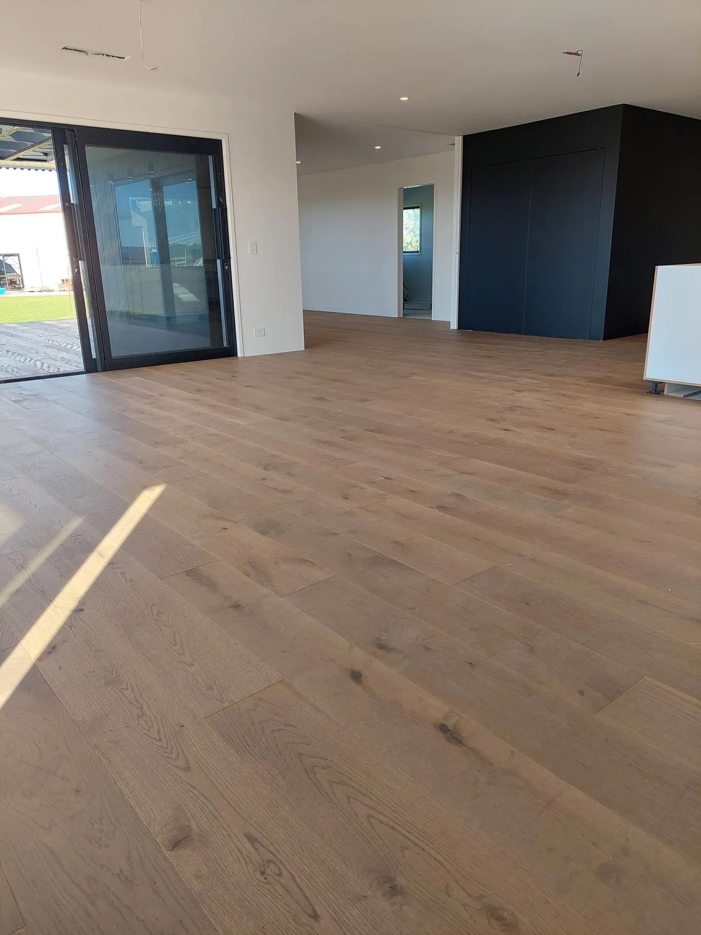 Wide oak floor in a bright living area.